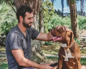 Ryan owner of Good Dog Sitting down patting a dog.